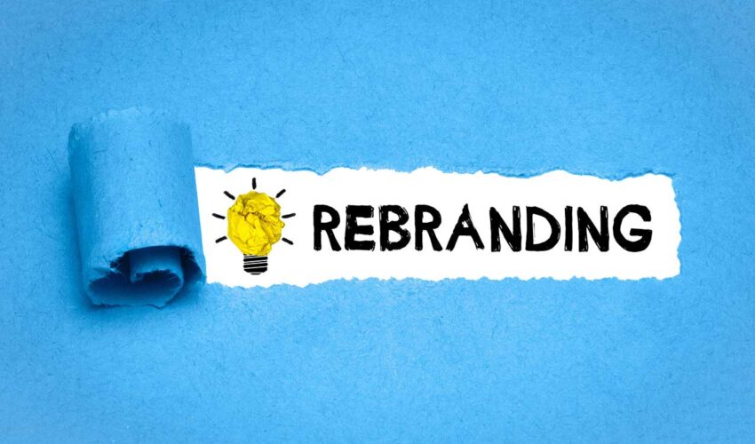 Schriftzug "Rebranding" wird hinter aufgerissener blauer Tapete sichtbar.