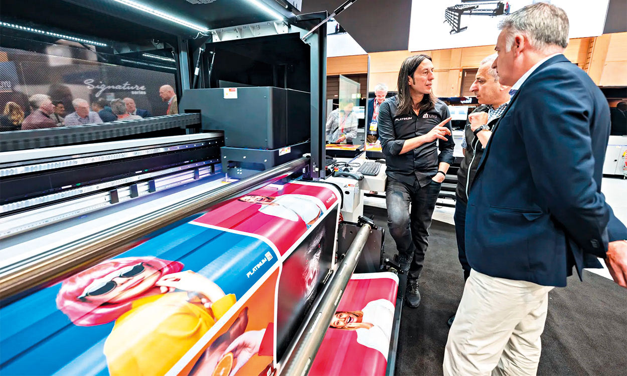 Interessenten bekommen an Messestand Drucker präsentiert.