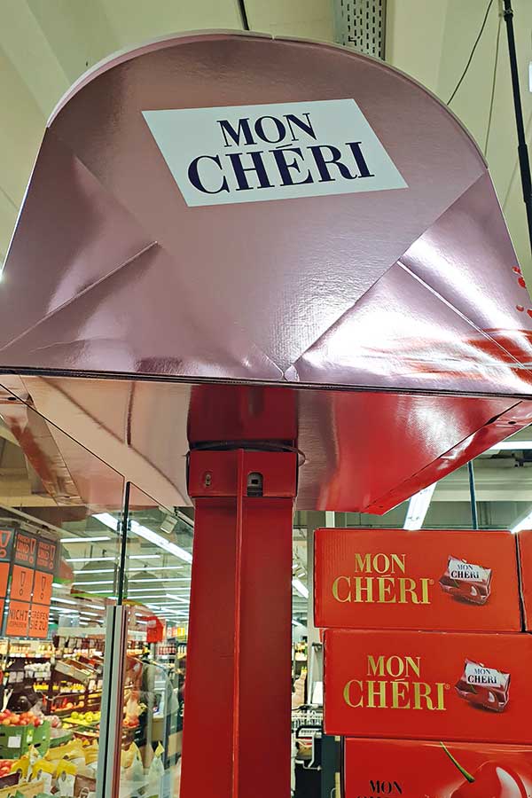 Beweglicher Schirm mit Aufschrift Mon Cheri überspannt Mon-Cheri-Trays.