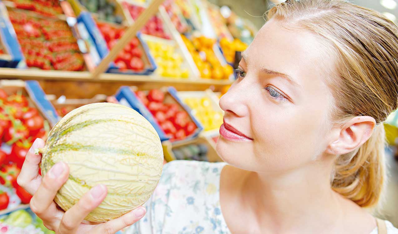 Frau schaut sich Melone an.