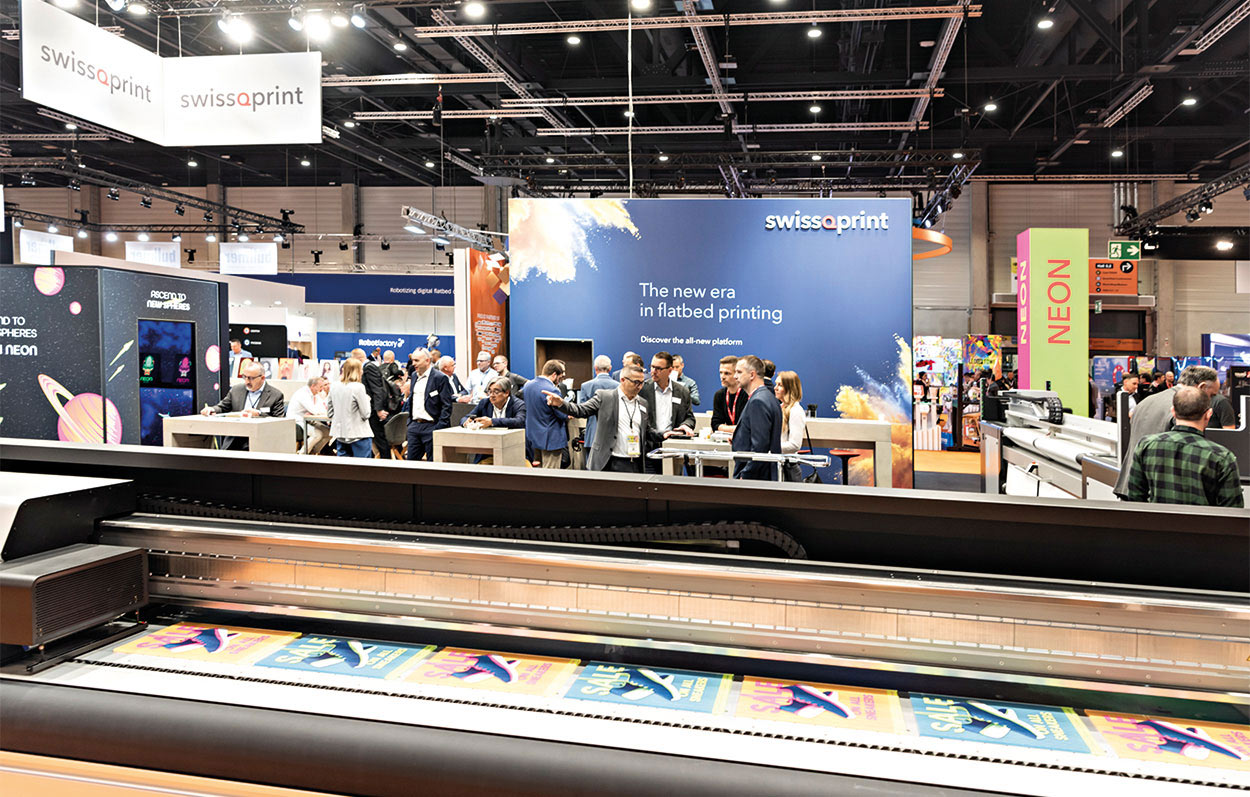 swissqprint-Stand auf Fespa mit Besuchern im Hintergrund.