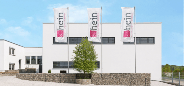 Hauptsitz Hein Verpackungen mit drei Fahnen mit Unternehmenslogo