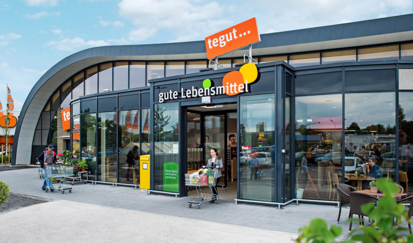 Kundin kommt mit Einkaufswagen aus tegut-Filiale