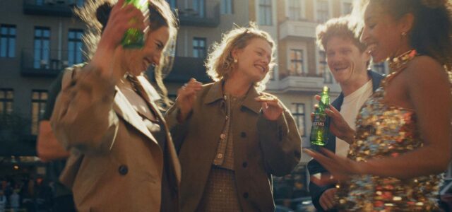 Junge Menschen stehen fröhlich biertrinkend zusammen