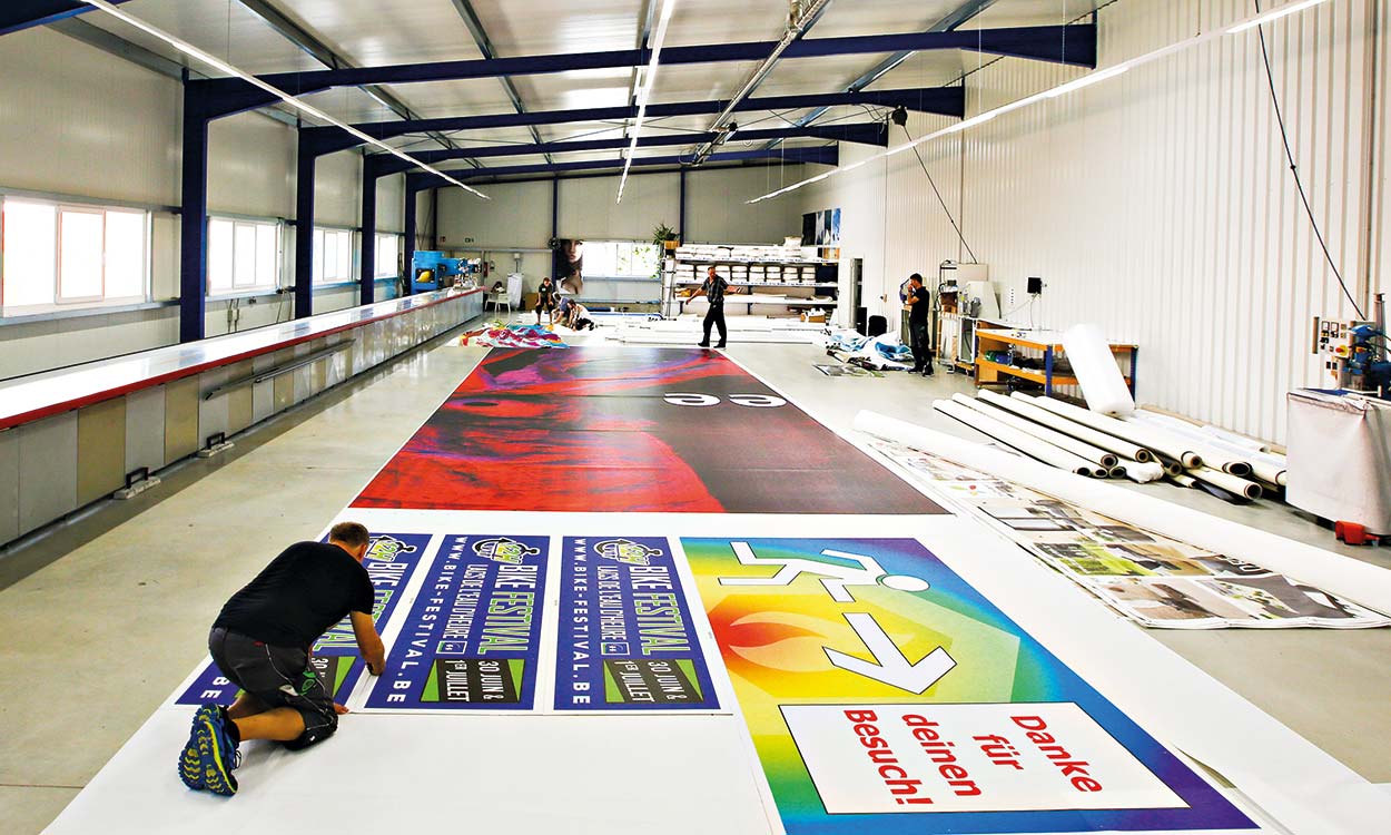 Mitarbeiter bearbeiten in Produktionshalle von GP German Printers Drucke