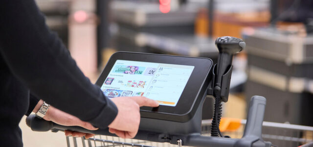 Kundin bedient Touchscreen an Einkaufswagen