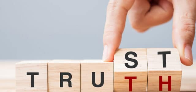 Hand dreht Bauklötze mit Aufschrift "Truth" und "Trust"